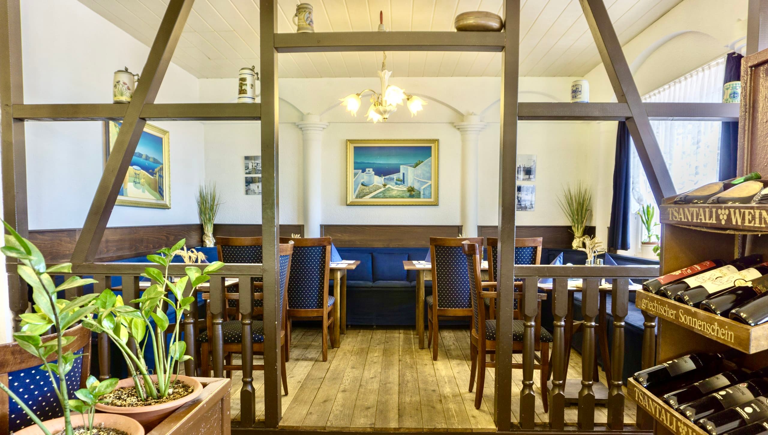 Gemütlicher Gastraum des Restaurant Zeus mit Fachwerk, blauen Sitzbänken und griechischen Gemälden